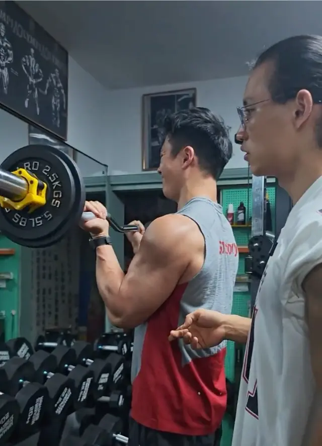 站姿杠铃弯举收缩位：杠铃举至胸前，大臂位置不变
